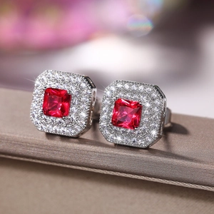 Macro shot of princess cut red zircon earrings with double halo stones on silk