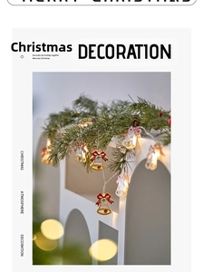 Close-up of LED Christmas bell string lights with red bows and holly on pine branches