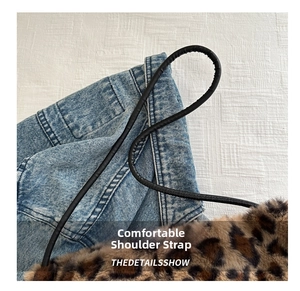 Detail of plush leopard print tote bag with thin black leather straps on denim background