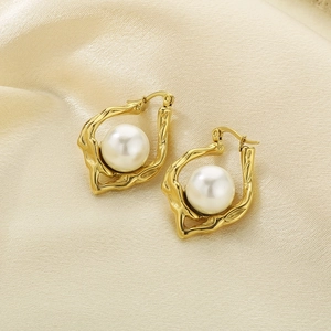 Detailed view of irregular gold hammer texture earrings with central white pearls on silk