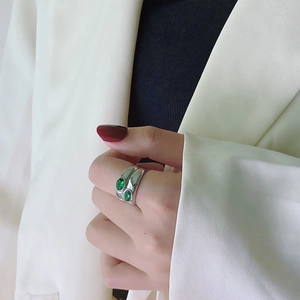 Close-up of a silver wide band ring set with dual oval emerald green gemstones