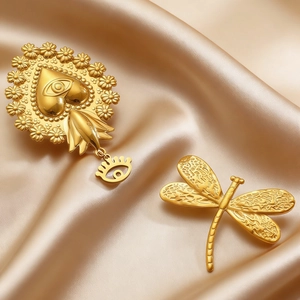 Detail of vintage gold heart pendant and dragonfly brooch on champagne satin fabric