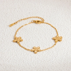 Detail of 18K gold plated stainless steel bracelet with three delicate floral charms