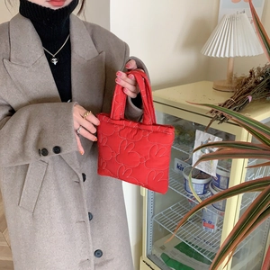 Detailed shot of red quilted handbag with white heart stitching and dual handles