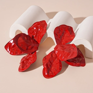 Macro view of red pleated flower petal earrings on a white aesthetic display stand