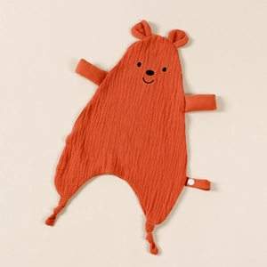 Detail of orange muslin cotton baby security blanket with embroidered bear face and knotted edges