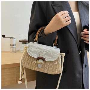 Detail of straw woven bag with floral embroidery and natural bamboo handle on model