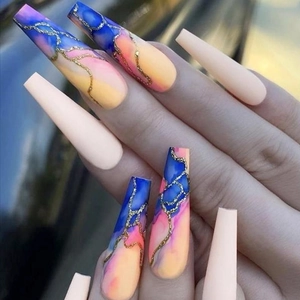 Long coffin press-on nails featuring nude tones and marble texture with gold glitter