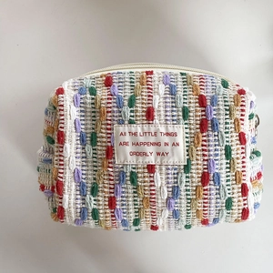 Macro shot of colorful woven makeup bag with orderly text label and beige zipper detail