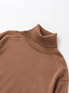 Detail of caramel high neck knit sweater showing ribbed collar and raglan sleeve seams