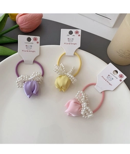 Detailed shot of fabric rose hair ties with pearls in purple, yellow, and pink colors