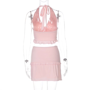 Detail of pink knitted two-piece set featuring halter neck top and ruffled mini skirt