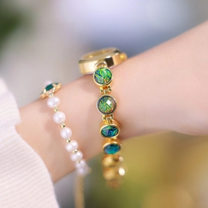 Close-up of golden vintage luxury watch with malachite texture and pearl bracelet
