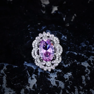 Macro detail of oval purple gemstone ring with wavy pavé diamond border on silver band