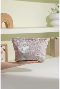 Détail d'une trousse de maquillage en jacquard rose fleuri avec étiquette de marque