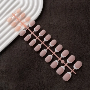 Row of oval French gradient press-on nails in nude pink and white on a display stand