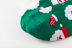 Detailaufnahme einer grünen Strickocke aus Baumwolle mit festlichem Weihnachtsmann-Muster