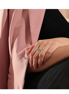 Close-up of bohemian gold ring with oval turquoise stone worn on hand by model