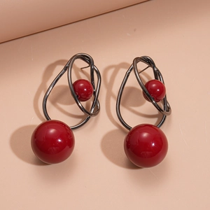 Detail of red acrylic ball earrings with black metal wire wrap and silver needle post