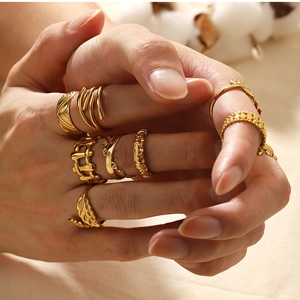 Close-up of stacked 18k gold plated stainless steel rings with floral and leaf designs
