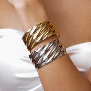 Gold and silver wide wave texture croissant cuff bracelets set on a model wrist