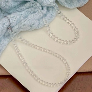 Minimalist clear crystal glass beaded necklace with silver clasp on white notebook