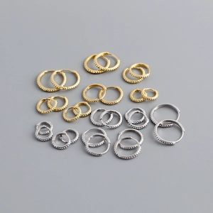 Macro detail of S925 sterling silver beaded hoop earrings in gold and silver variety