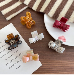 Close-up of elegant acetate bow hair clips in various colors on a dark wooden surface