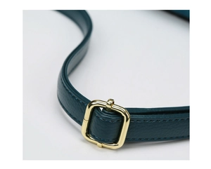 Detail of lychee pattern leather shoulder strap with polished gold metal buckle and stitching