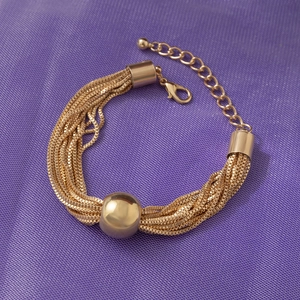 Detail view of gold multi-layer chain bracelet featuring a large smooth central bead