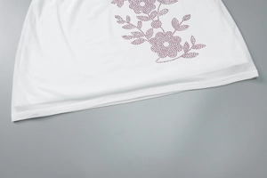 Detail of purple floral rhinestone pattern on white knitted crop top fabric