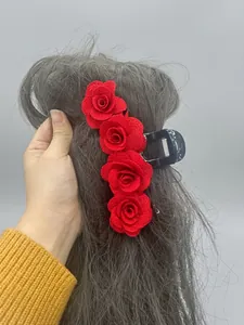 Detail view of a large hair claw clip with red velvet roses on long dark hair
