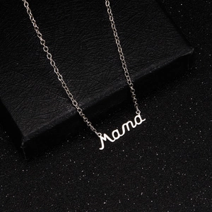 Macro shot of silver Mama pendant necklace on black textured jewelry gift box