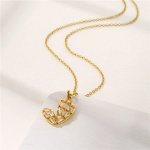 Elegant gold cactus necklace with clear zircon stones on a white textured surface