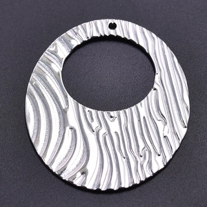 Macro shot of silver 304 stainless steel oval pendant with wavy texture and hollow design