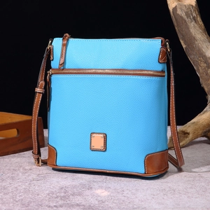 Detail of sky blue pebble grain leather crossbody bag with brown trim and metal zipper