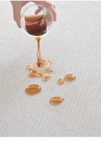 Close-up showing waterproof fabric resistance with liquid beading on cream rug surface