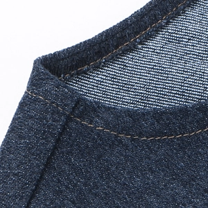 Detailed macro view of dark blue denim fabric with precise contrast stitching on the edges
