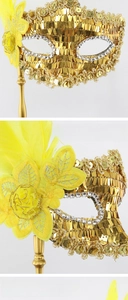 Detail of golden sequin masquerade mask with yellow lace flowers and soft feathers