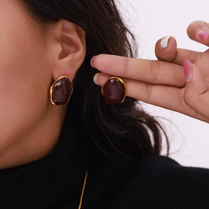 British vintage style gold-rimmed brown enamel earrings worn by a model