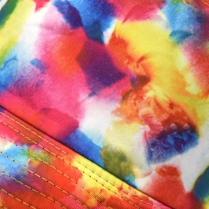 Detailed close-up of colorful tie-dye fabric with precision yellow stitching on hat brim