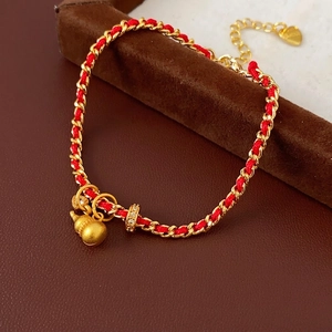 Bracelet corde rouge plaqué or avec pendentif gourde et breloque cœur sur fond de cuir