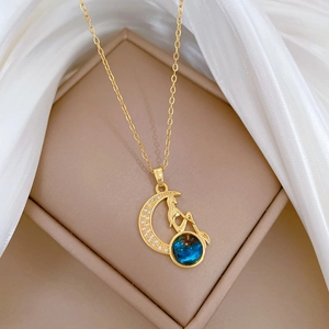Detailed close-up of a crescent moon necklace with zircons and a teal gemstone