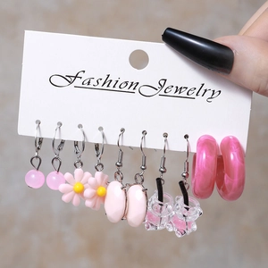 Close-up of pink themed earrings set including daisy and resin cup styles on a card