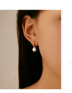 Close-up detail of silver S925 pearl hoop earring worn by a model in soft light