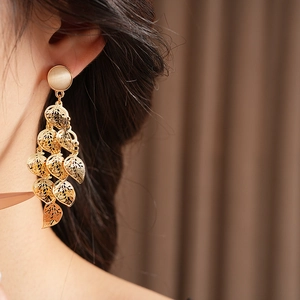 Detail of gold multilayer hollow leaf tassel earrings with cat eye stone on a model