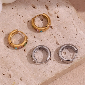 Gros plan de boucles d'oreilles dorées et argentées serties de zircons colorés