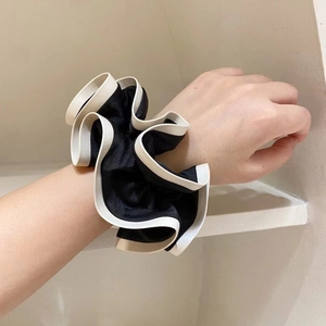 Elegant French style black and white satin scrunchie with soft ruffled texture on wrist