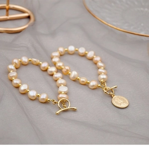 Set of two champagne baroque pearl bracelets with golden T-bar clasps and coin pendant