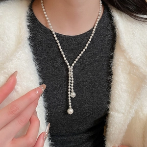 Detail of vintage glass pearl Y-necklace with teardrop pendant on a model's neck